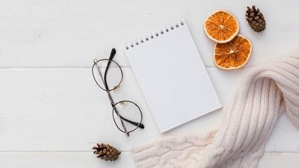Workspase with notebook, glasses, cozy scarf and cup of coffee with milk on white wooden background. Autumn creative composirion flat lay. Work, online education, goals to do list, home office concept
