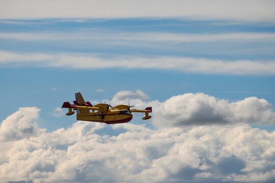 Firefighting aircraft flying over dramatic layered clouds.