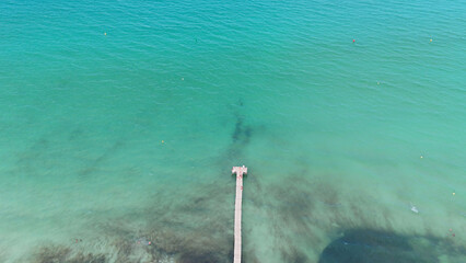 Playa de Muro, Mallorca. Scenic aerial view of a wooden pier extending into clear turquoise waters,...