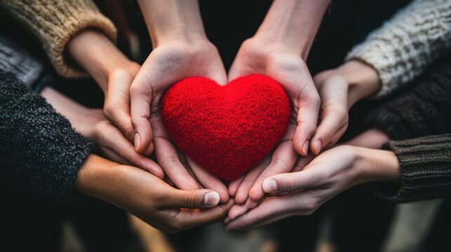 Hands reaching together with symbolic red heart shape, concept of collective donation and kindness for Giving Tuesday support