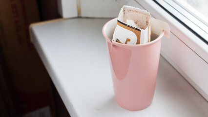 Drip bag in a ceramic cup on windowsill. Instant freshly brewed alternative filter drink in mug. Easy brew black coffee method for home, travel or office. cozy trendy lifestyle