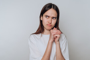 Young woman in white shirt looking skeptical with folded hands.