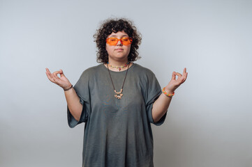 Person meditating with orange sunglasses and casual attire.