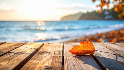 Lonely autumn leaf on a wooden table by the sea, with soft side lighting and slightly blurred background