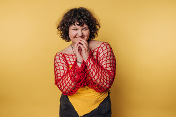 Smiling person in a red net top against a yellow background.
