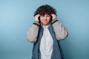 Person with curly hair in a denim jacket looking frustrated.