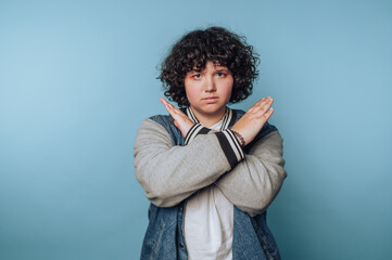 Person with curly hair making an X gesture with arms.