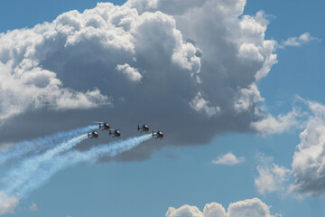 Four helicopters performing aerobatic display with smoke trails.
