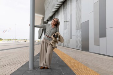 Woman in light attire leans against pole while exploring modern architecture during daylight
