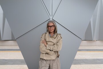 Modern woman poses confidently in urban setting with geometric architecture in the background...