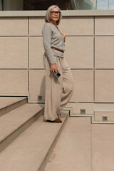 Woman in stylish outfit posing at modern architecture steps during daylight in an urban setting
