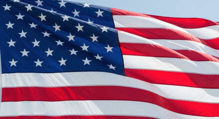 Obraz premium Close up of the american flag waving gently in the breeze on a bright sunny day with clear blue sky