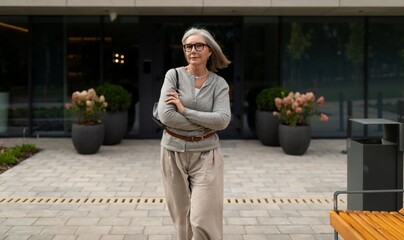 Senior woman confidently walking in a modern urban setting during daylight