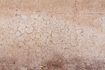 Close-up of cracked plaster wall surface with natural texture and rough details