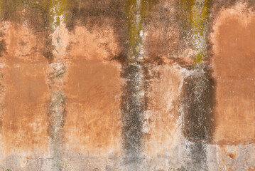 Old plaster wall with stains and weathered textures in earthy orange tones
