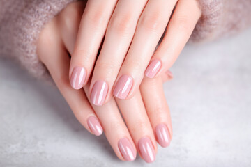 Naklejka premium Elegant hands display a soft pink manicure. The nails are neatly shaped and glossy, creating a polished and feminine look.