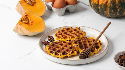 Autumn breakfast scene with pumpkin waffles and honey on marble table. Pumpkin recipes.