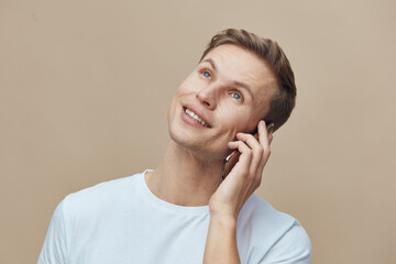 Friendly man with short brown hair talking on mobile phone looking up smiling cheerful casual wear...