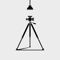 Vintage camera on tripod illuminated by spotlight in studio