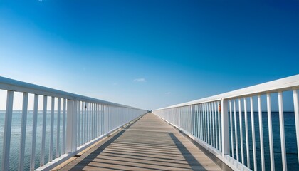 Obraz premium a serene minimalist walkway stretches into the distance framed by white railings under a clear blue sky evoking tranquility and openness