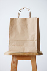 Brown paper bag on wooden stool against white background