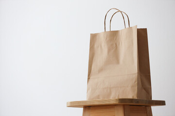 Brown paper bag on wooden chair against plain white background