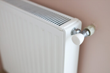 White home radiator with control valve on pink wall for efficient heating