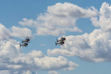 Three helicopters flying in formation against dramatic clouds.