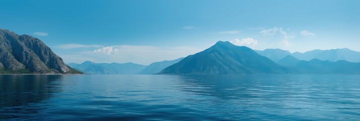 Fototapeta premium Serene mountain landscape overlooking calm blue lake under clear sky