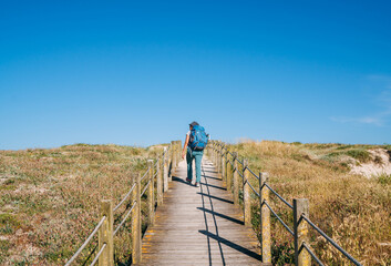 Middle-aged woman with backpack walking in Portugal on the Camino Portuguese — a popular pilgrimage route to Santiago de Compostela. Concept of active lifestyle, travel, and happiness. © Soloviova Liudmyla