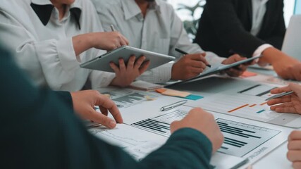 A diverse business team engages in a collaborative meeting, analyzing data and strategizing on project presentation, emphasizing teamwork and technological integration. SACTR - Powered by Adobe