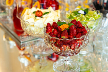 Luxury catering setup with strawberries, pineapple and lime in crystal bowls, elegant buffet decoration for cocktails and events