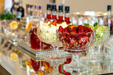 Elegant catering table with strawberries, pineapple and lime in crystal bowls, luxury cocktail garnish and event decoration