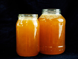 Two glass jars of fine golden honey on dark background. Fine natural product, food and agriculture industry.