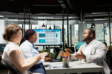 Recruiters team conducting interview with black man applicant, going through the hiring process by discussing job expectations, qualifications and evaluating the resume and in detail.