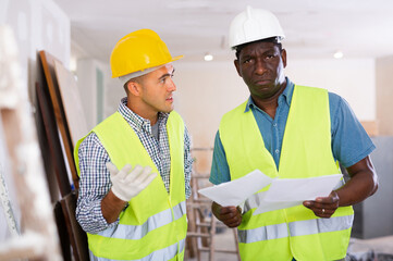 Two engineers discussing blueprints in a renovated room