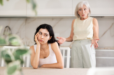 Elderly woman during family quarrel with young woman in kitchen at home