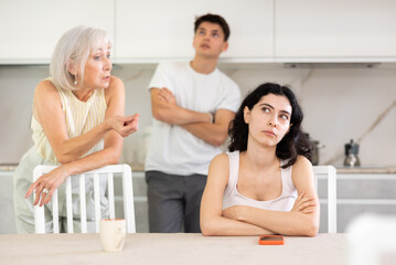 Upset woman dont speaking after discord with mother and husband standing behind