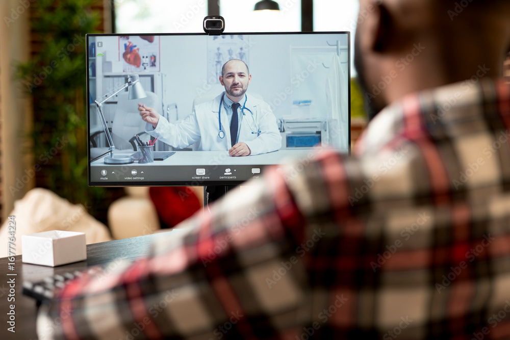 Poster self employed man sits at desk using computer for video call with caucasian general physician. docto