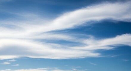 Fototapeta premium Wispy Clouds Drifting Across a Blue Sky.