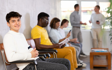 Portrait of a young man sitting in a chair in the lobby waiting
