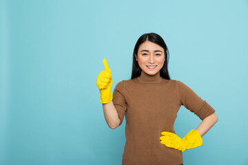 Cheerful female housekeeper poses proudly, showing thumbs up to express joy after completing...