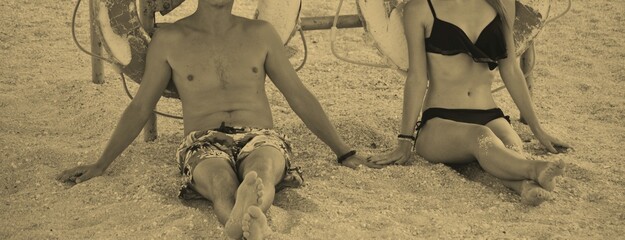 A man and a woman walking hand in hand along the seashore, in summer you can see the water, people, a woman in a black swimsuit, paern in light shorts