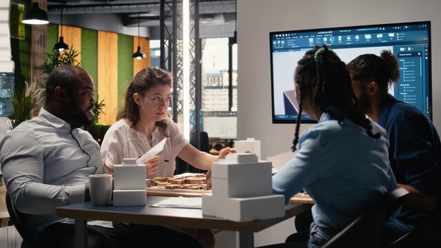 Real estate team using 3D models to explore construction layout options, working on residential project for urban development phase during a strategic office meeting with contractors.