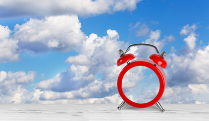 red alarm clock without dial against blue sky