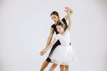 Mother and daughter ballet dancers against white background