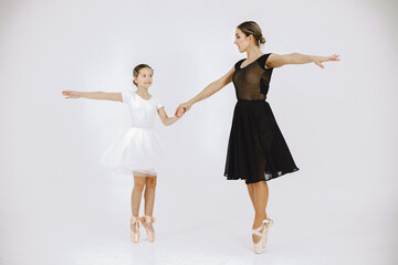 Mother and daughter ballet dancers against white background