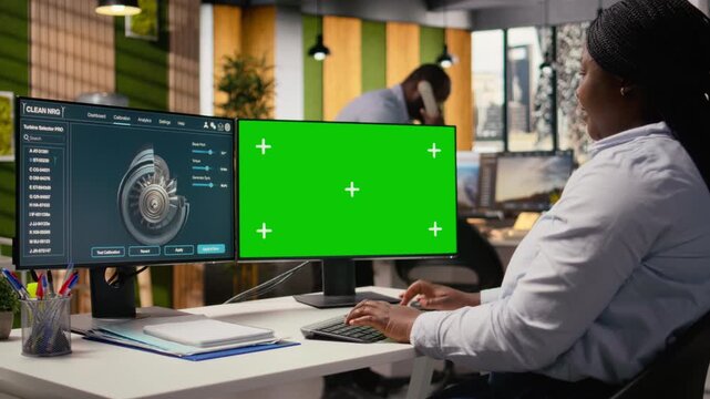 Female technician using CAD tool on isolated screen computer to reduce carbon footprint of wind turbines. Woman in RD office upgrading eco friendly windmill parts on mockup PC, camera A
