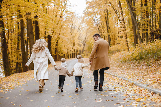 Backside photo of young family on a walk in autumn forest