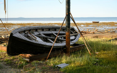 Abandoned wooden boat on empty beach with clear sky by White Sea in summer in Karelia, concept of...